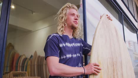 hombre caucásico fabricante de tablas de surf sosteniendo una tabla de surf nueva