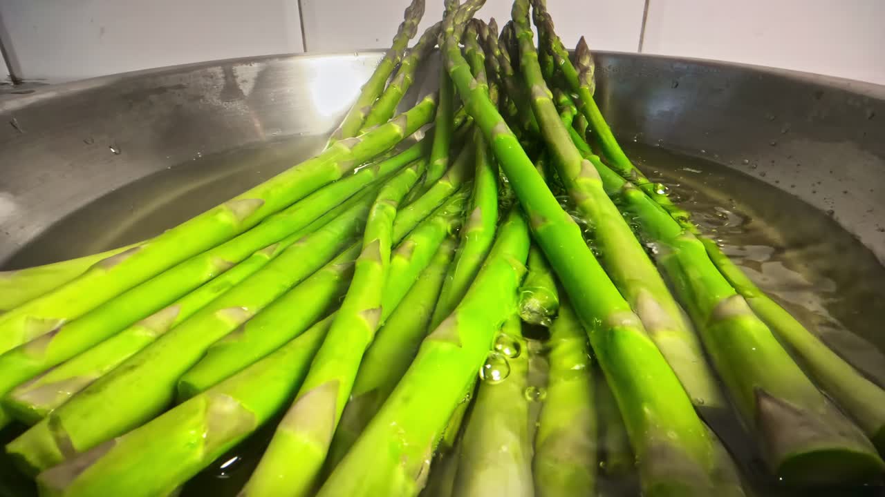 Gli asparagi bollono in acqua fumante all'interno di una pentola in acciaio inossidabile durante il processo di cottura