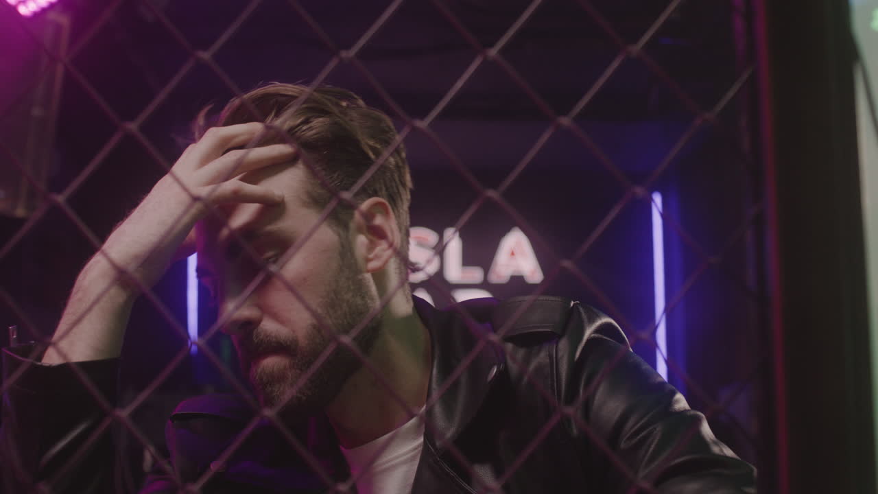 retrato de un hombre triste sosteniendo una botella de cerveza mientras se sienta en la discoteca