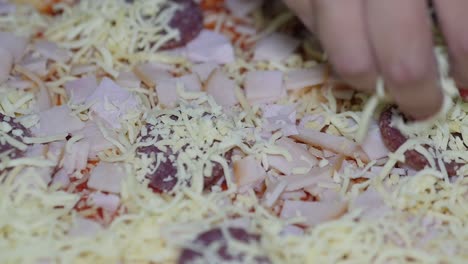 extreme close-up of sprinkling cheese on a homemade pizza