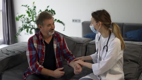 doctor measure pulse of senior man at home