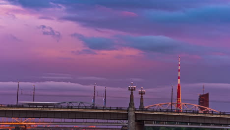 Riga-TV-tower-bridge-for-cars-over-Daugava-river-with-colorful-sunset-sky,-fusion-time-lapse