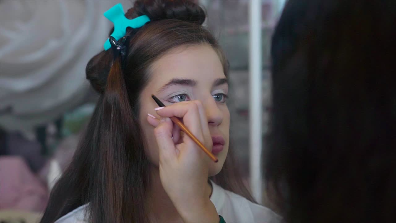 una adolescente se hace el maquillaje y el cabello
