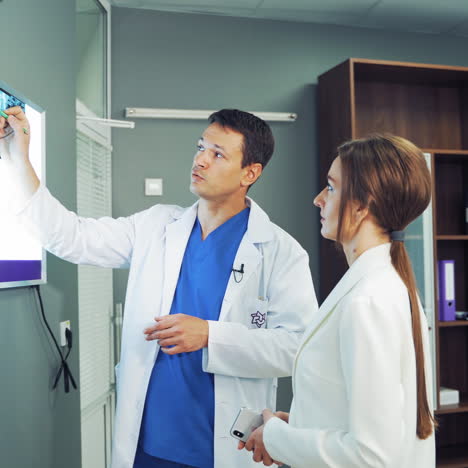 doctors having a conversation while looking at x-ray photograph. spinal tomography is hanging on the white board and specialists in medical uniform discussing the results.