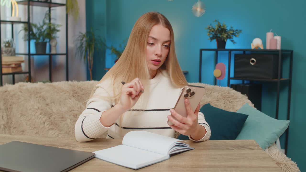 Woman talking on smartphone video call in serious business negotiation at home on sofa making notes