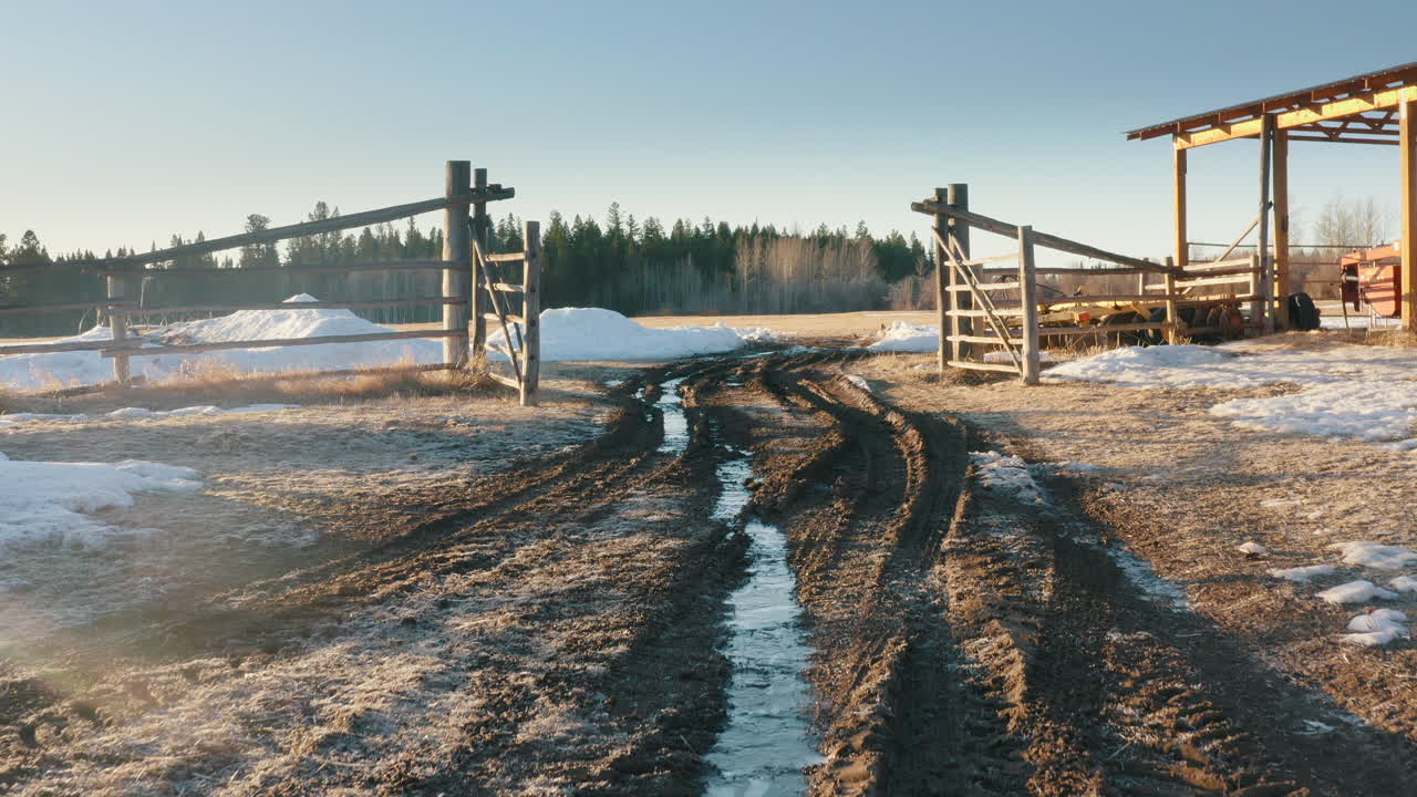 elevación aérea desde el camino de tierra que revela la puerta del rancho y el campo de cultivo