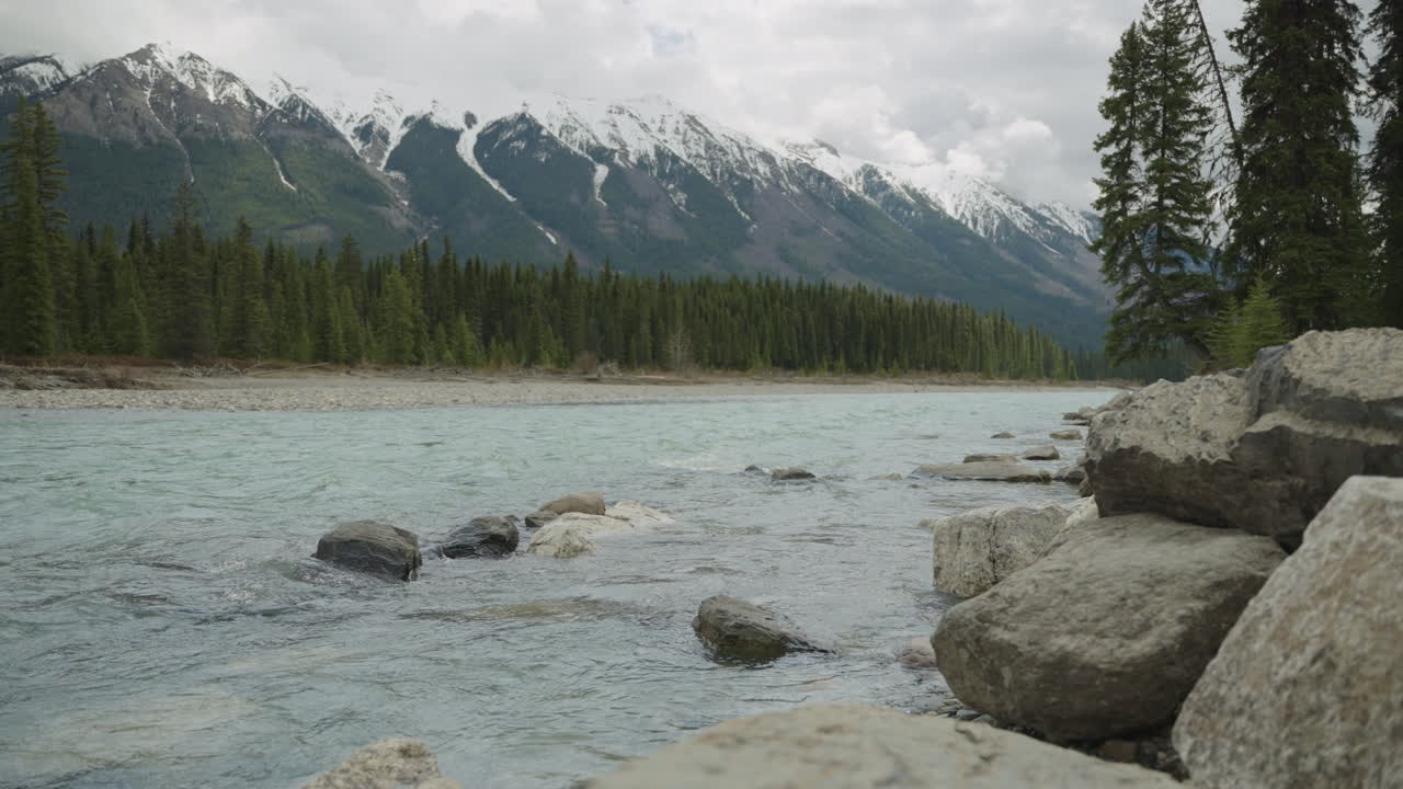 un arroyo con montañas cubiertas de nieve en el fondo, en las montañas rocosas canadienses