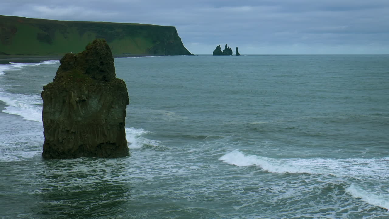 imágenes en cámara lenta de las olas del océano en la playa de arena negra reynisfjara con reynisdrangar - rocas marinas de basalto situadas bajo la montaña reynisfjall, cerca de la aldea de vik i myrdal en islandia