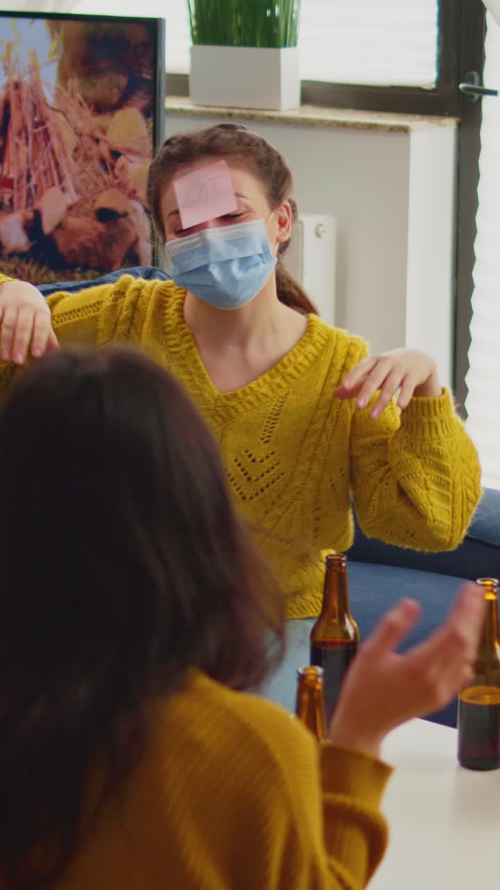 Vertical video: Funny friends with sticky notes on foreheads enjoying name game