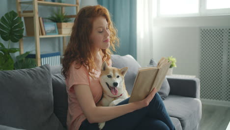 woman reading with her shiba inu dog on a sofa