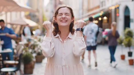 young woman shouting, celebrating success winning goal achievement good victory news in city street