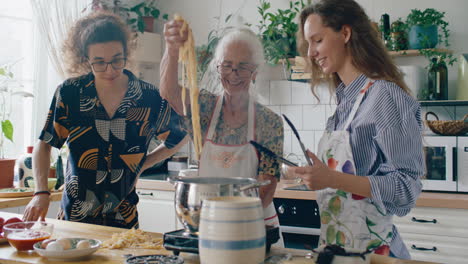 grandmother cooking fresh pasta in boiling pot with help of grandkids