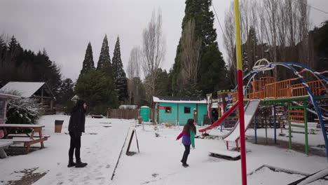 child playing on snowy playground with parents nearby, winter joy in patagonia, argentina