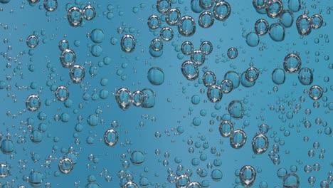 beautiful bubbles in a glass of sparkling water on a blue background beautiful bubbles in a glass of sparkling water on a blue background fascinating movement under the glass slow motion close up