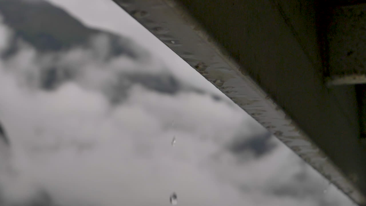 Slow motion rain drops fall off side of boat with out of focus cloudy mountains behind - Doubtful Sound , New Zealand