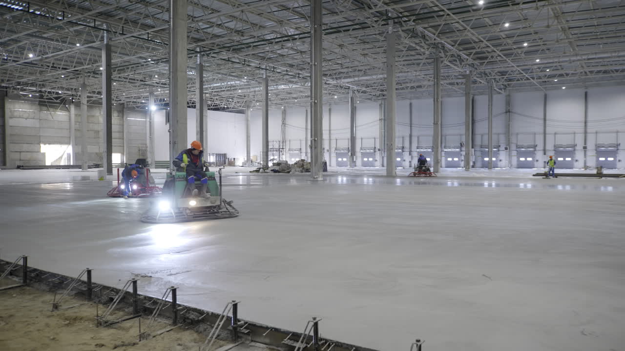 trabajadores de la construcción vertiendo el piso de hormigón en un gran almacén