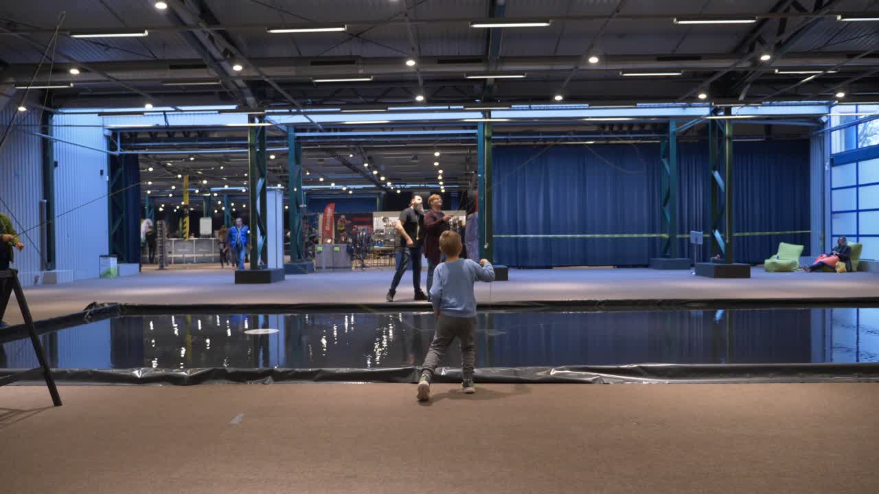 kid trying to hold and use fishing rod, indoors practice room