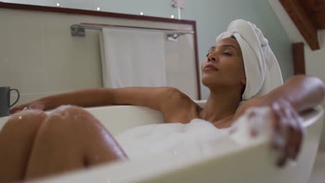 mixed race woman wearing towel on head taking a bath