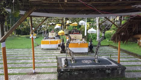 Outdoors-Temple-Court-in-Bali-Indonesia-Calm-Vibrant-Garden-around-Hindu-Religious-Umbrellas-and-Architecture,-Ancient-White-Trees,-Pura-Samuan-Tiga-in-Bedulu