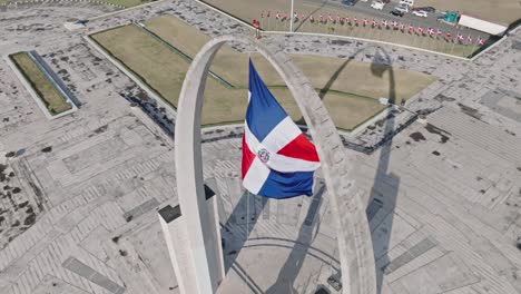 dominican republic flag at triumphal arch in flag square, santo domingo, dominican republic - aerial, slow motion