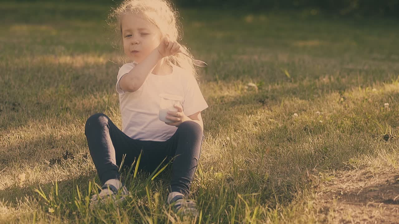 una joven de cabello rubio sostiene una cuchara bonita y una taza blanca