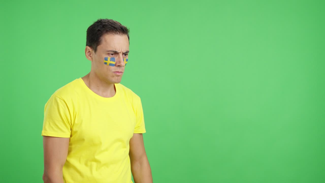 Man with swedish flag painted looking away with serious expression