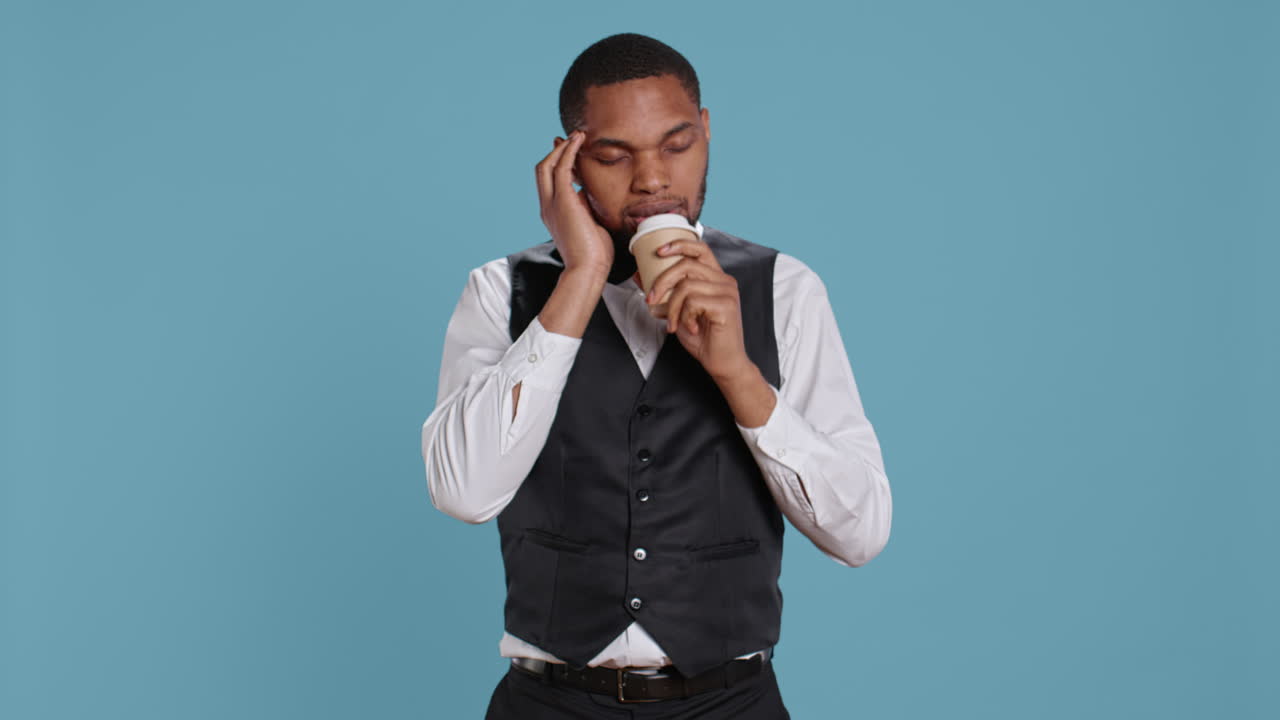 불안한 호텔 포터는 아프고 커피 한 잔을 마시고 있습니다.