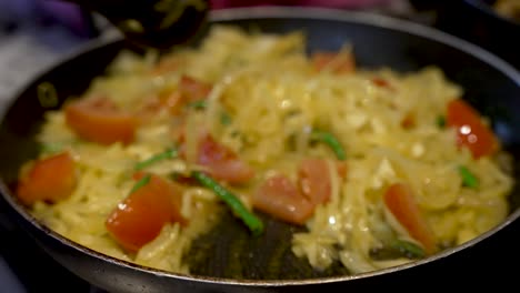chef revuelve cebollas picadas tomates picados y chiles