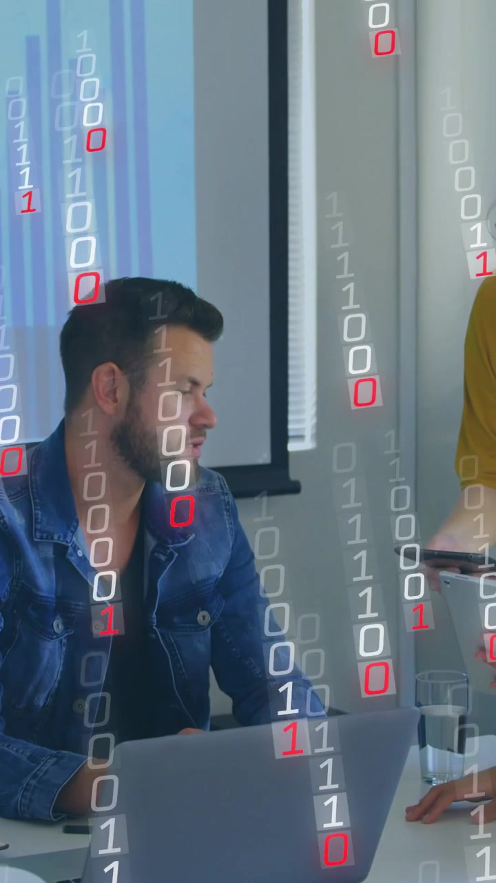 Vertical video: Man leaning at laptop woman placing tablet making 0s1s rain over bar chart for tech