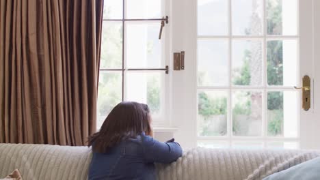 Video-of-sad-asian-girl-looking-outside-window