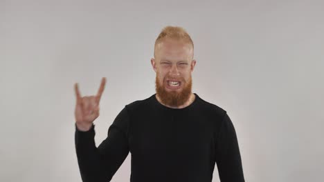 red-haired guy with a beard shows the sign of heavy metal