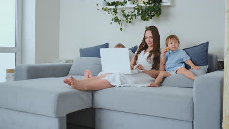 beautiful young mom and two little kids boys are looking at the laptop screen family photos. and make online shopping