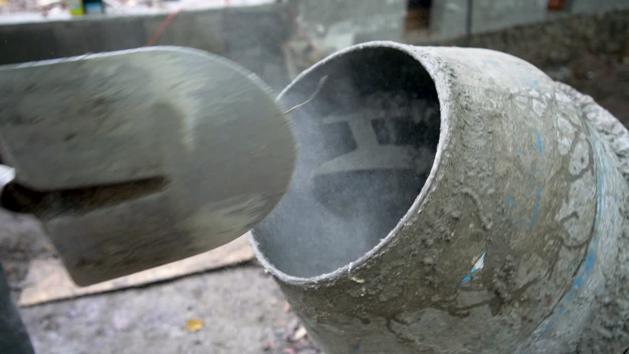 Construction worker shoveling cement into a cement mixer