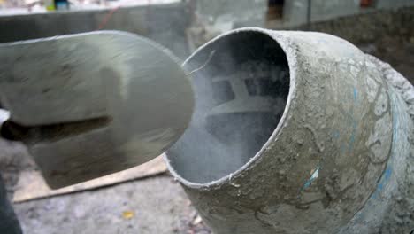construction worker shoveling cement into a cement mixer