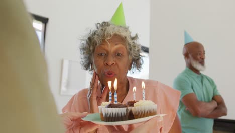 happy senior diverse people at birthday party with cake at retirement home