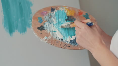 the hands of an unrecognizable girl mixing colors on the painter's palette