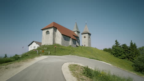 steady shot of old church on the top of the hill near route and the forest, kum slovenia