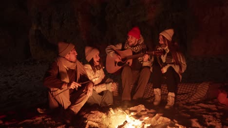 friends singing around a campfire on the beach at night