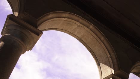 stone archway and pillar with sunlight illuminating the structure against a clear sky