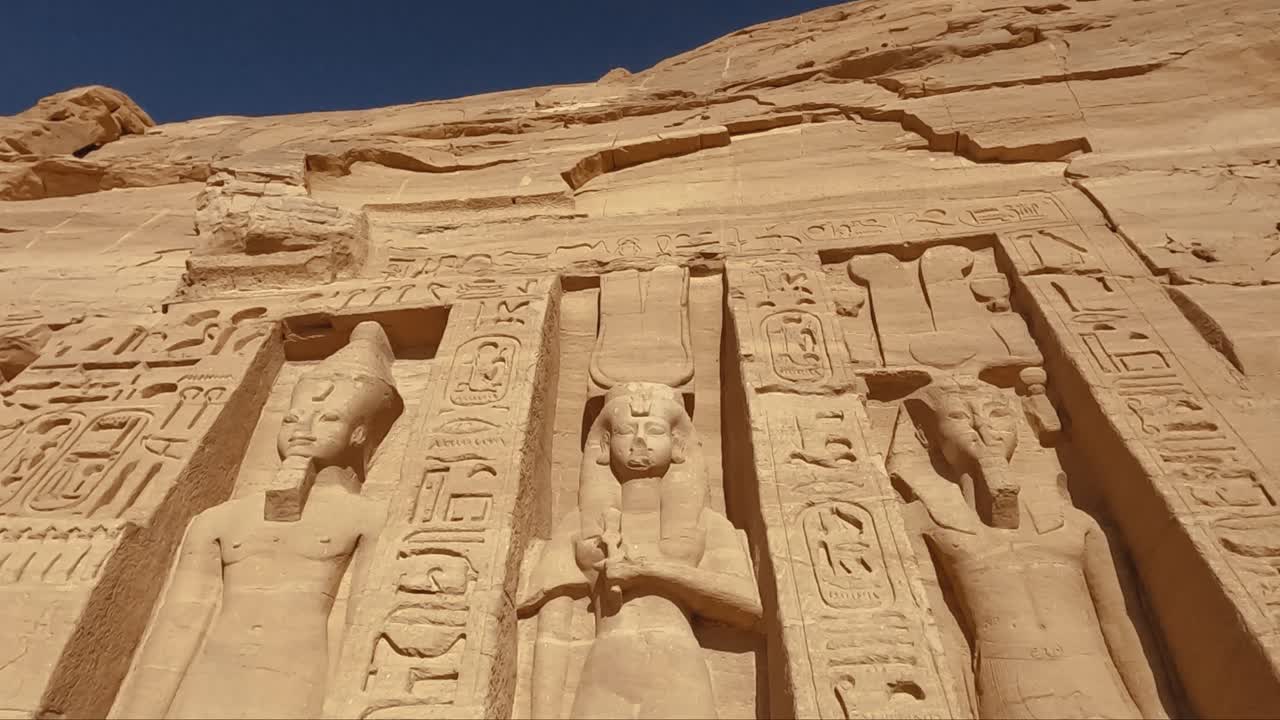 Detailed close-up view of the monumental statues and hieroglyphic inscriptions at the Abu Simbel Temple in Egypt. Carved into sandstone, these ancient figures represent Pharaoh Ramesses II.