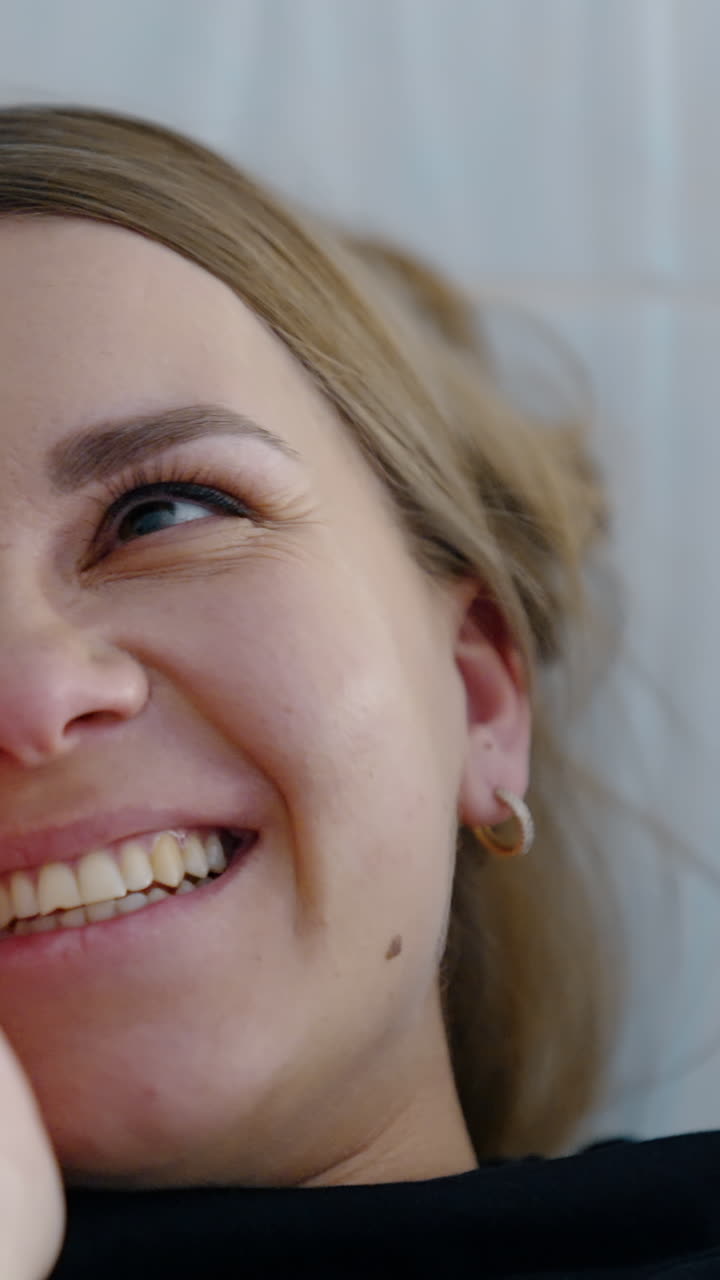 Smiling face of a woman at ultrasonic examination. Future mom is drying her tear of happiness from eye. Close up. Vertical video