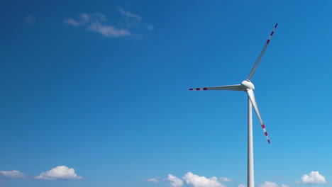 spinning blades of single wind turbine against blue sky with text space