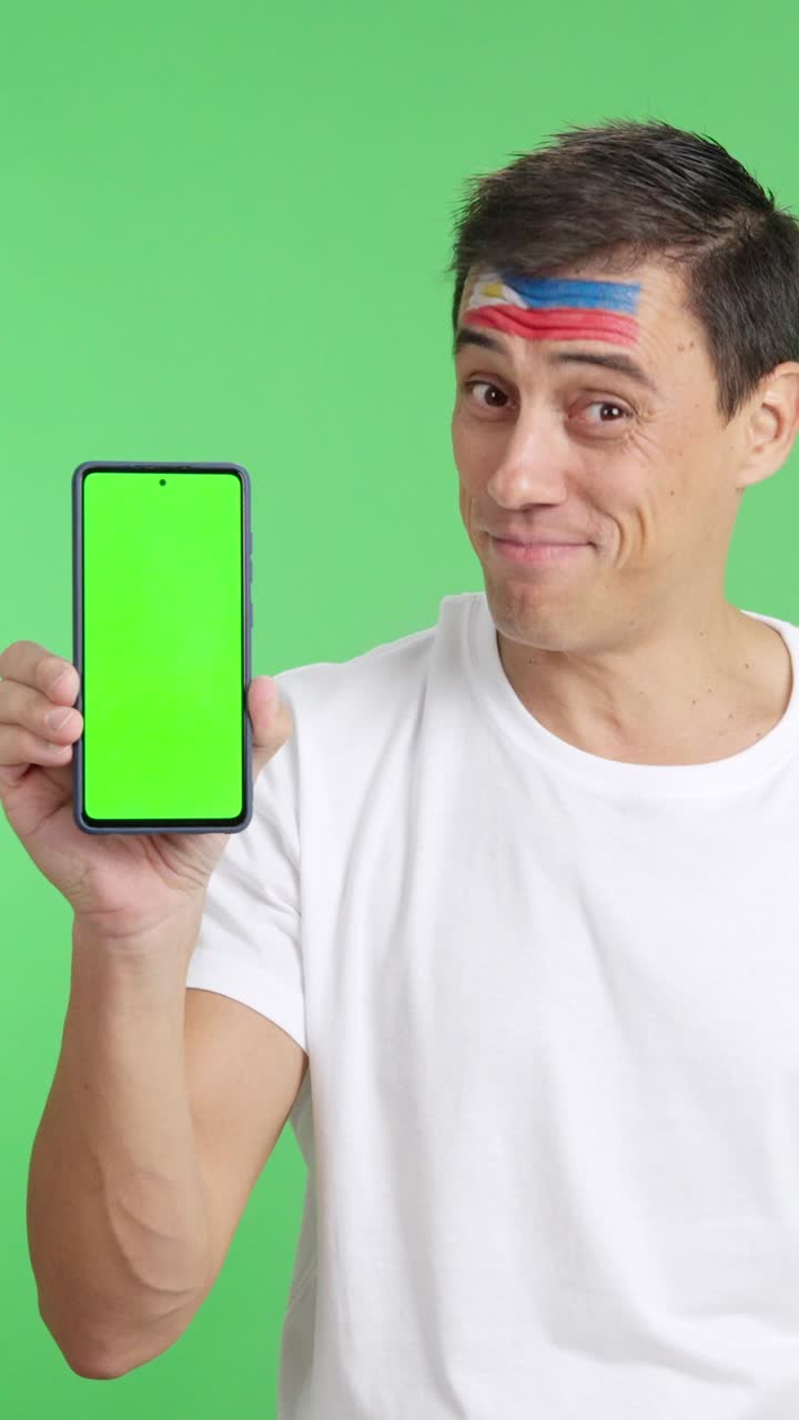 Philippines supporter looking at his mobile smiling and showing it