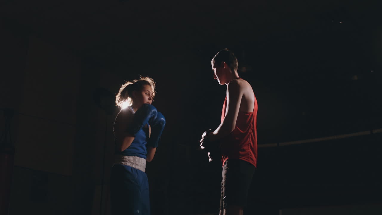 mujer adulta joven haciendo entrenamiento de kickboxing con su entrenador.