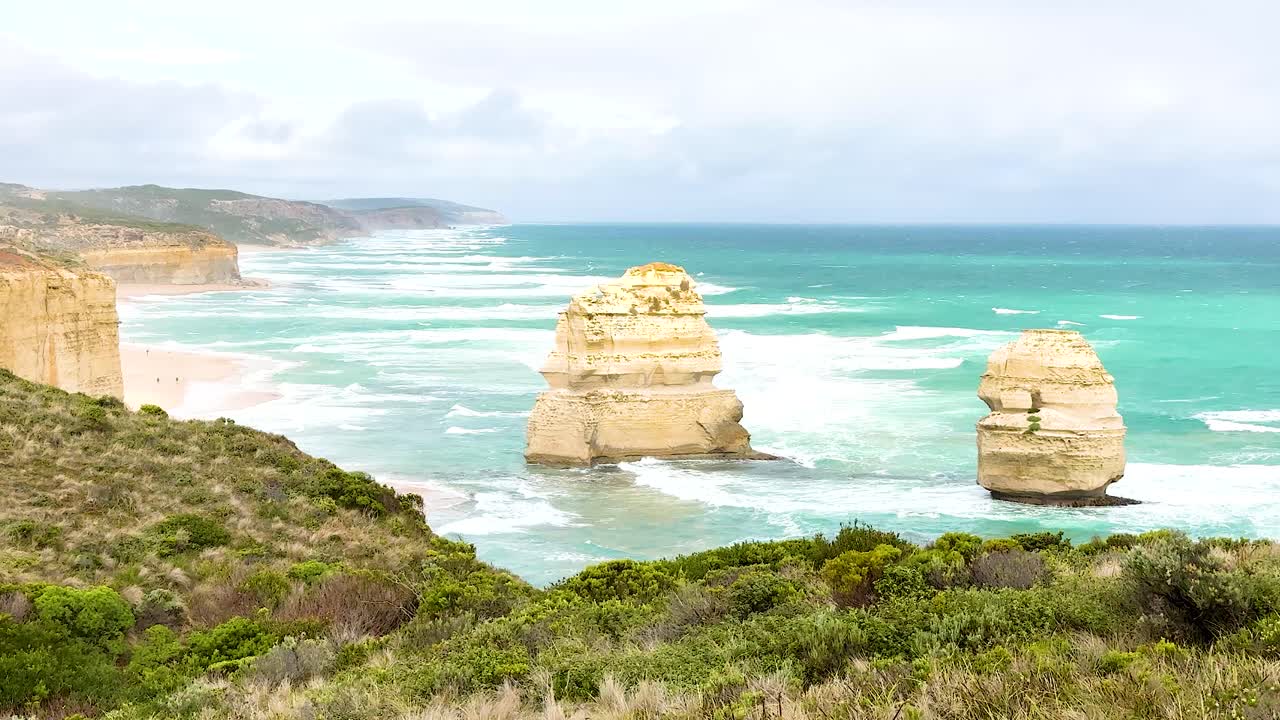 A serene view of the Twelve Apostles with turquoise waters and rugged cliffs under soft daylight at Port Campbell, Australia