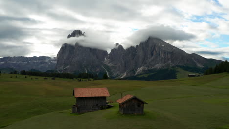 italian cottages on alpine plateau with dolomites in distance