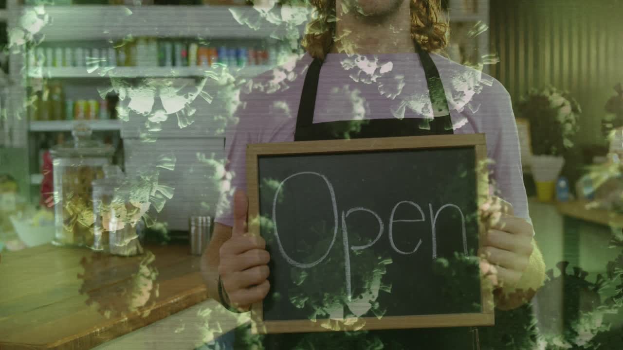 Animation of macro Covid-19 cells floating over happy Caucasian male chef holding Open sign