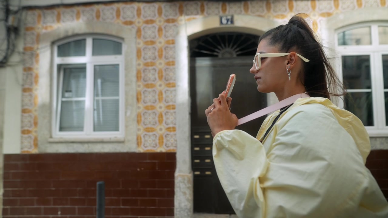 Young Woman Walking Through European City Street Using Smartphone