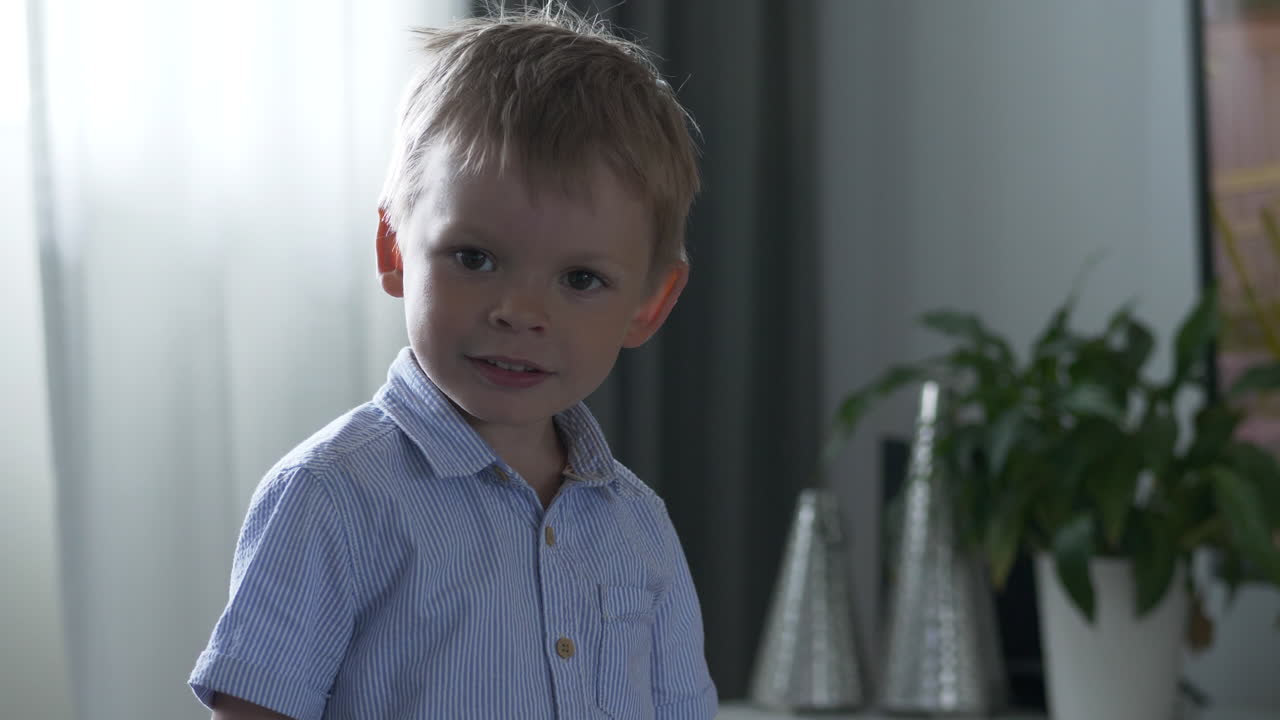 Young stylish and curious boy turns glance towards camera, indoors