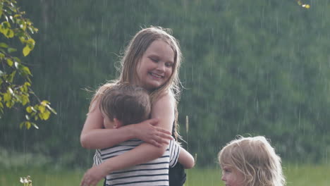 happy sibling hugging and smiling in summer rain